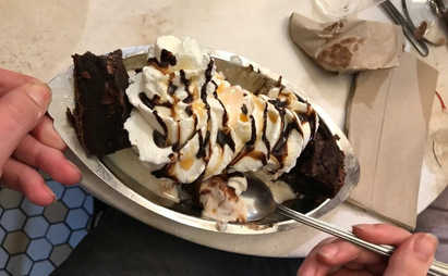 A sundae with a brownie, chocolate syrup, nuts, and whipped cream